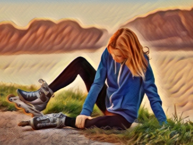 Young woman on roller skates sitting on ground, injured from falling or spasm, holding her leg. About 20 years old, Caucasian blonde in sports clothing.
