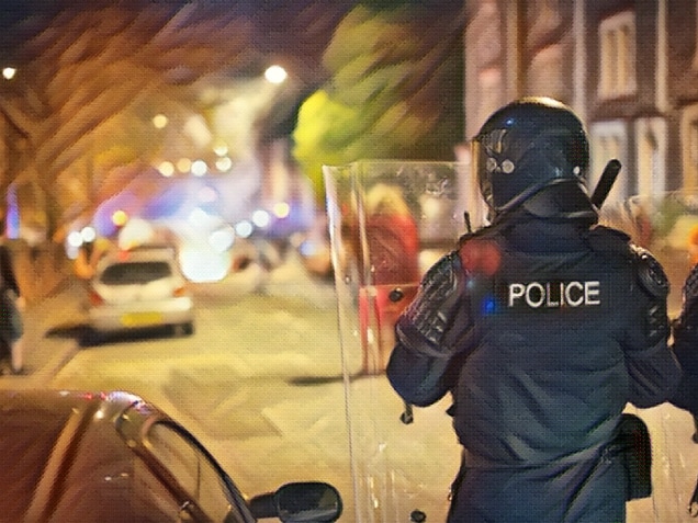 Riot police move forwards towards burning waste bins and rioting.