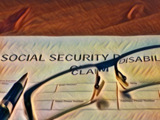 someone filling out social security disability claim form on the background and pen with glasses on top of the form