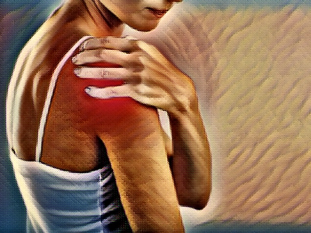 Woman is touching her painful, injured shoulder with her hand
