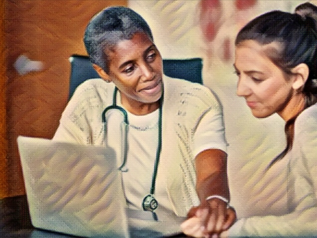 A doctor and patient are discussing the patient's medical history using a laptop. The doctor is comforting the patient.