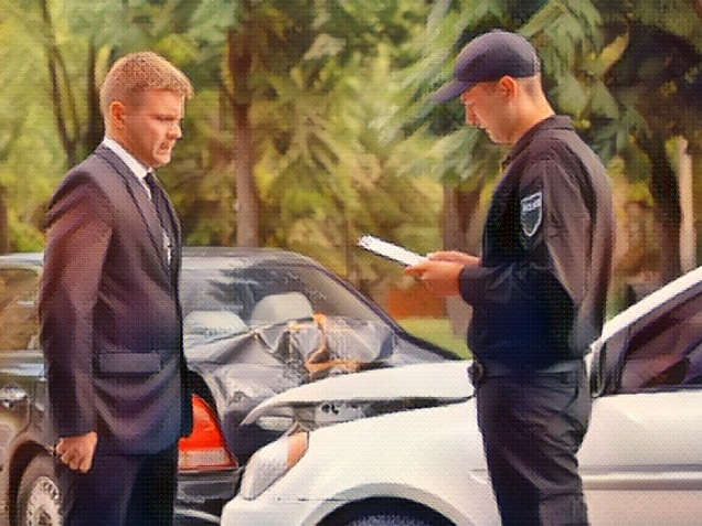 Stressed male driver looking policeman filling car accident report