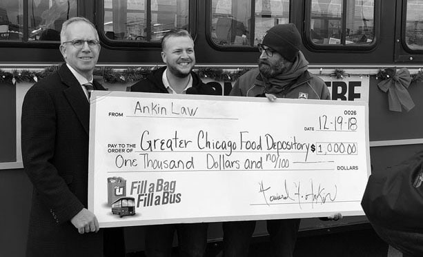 Howard Ankin holding a checque with Fill a Bag Fill a Bus