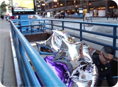 man emerging from the subway carrying balloons