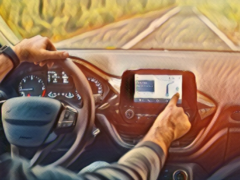 Male driver using dashboard screen maps while driving on road in autumn warm colors