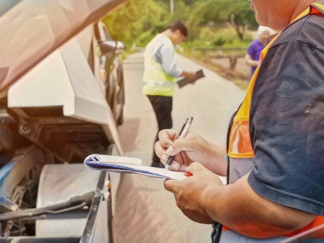 Closeup and cropped insurance agent writing on clipboard while examining car after accident claim being assessed and processed