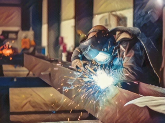 Industrial Welder With Torch and Protective Helmet in big hall welding metal profiles