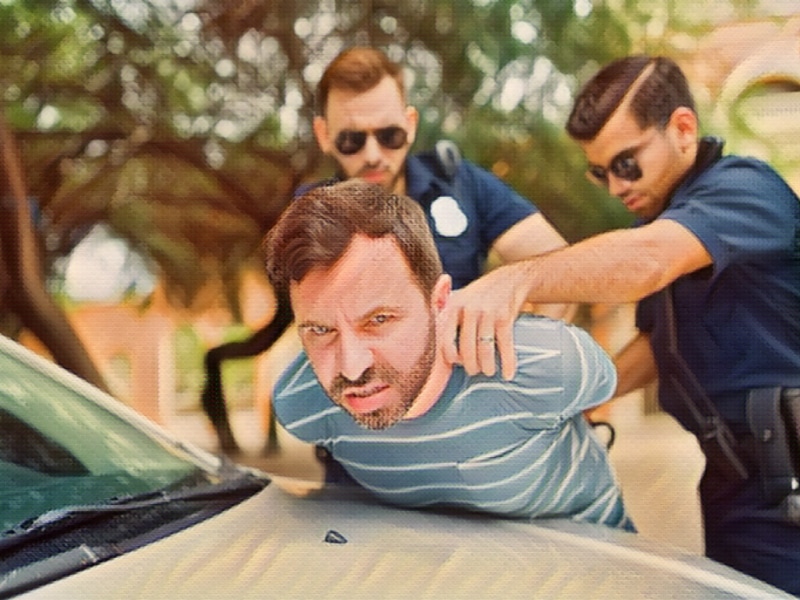 Angry young man looking upset and agressive while getting arrested by two cops putting handcuffs for committing a crime. concept of What is police brutality