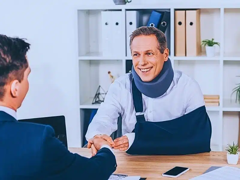 Man in neck brace with broken arm and businessman in shaking hands. How to Find a Medical Malpractice Attorney.