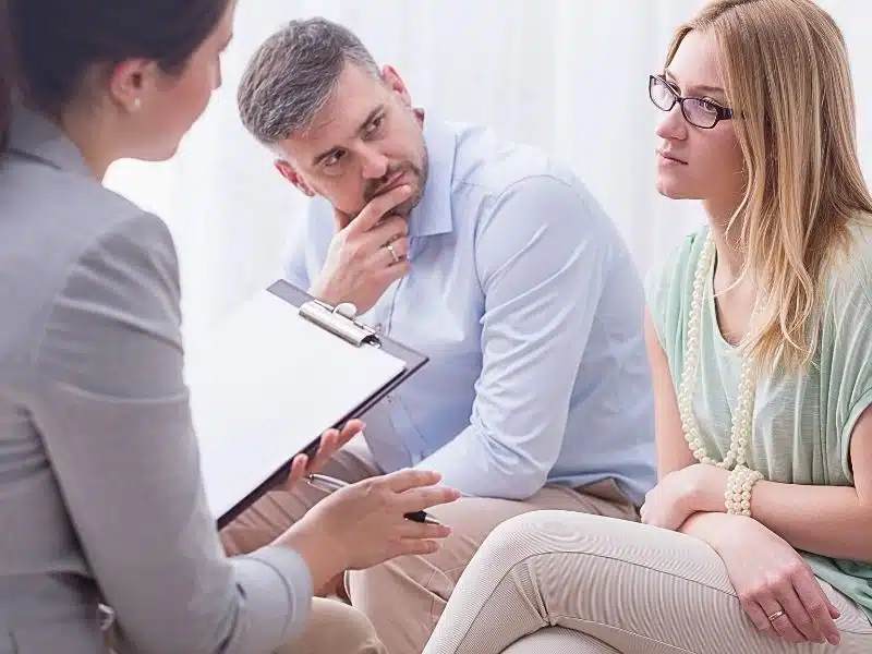 Upset young woman beside her husband talking to a female doctor. Elmiron vision loss claims.