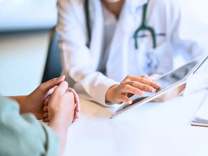Shot of a doctor showing a patient some information on a digital tablet. What cancers are related to hair relaxers?