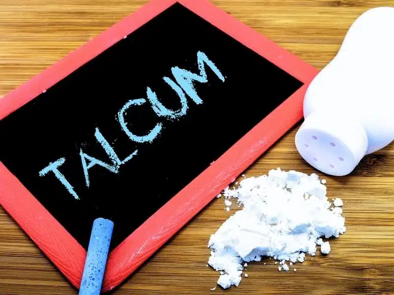 Talcum written on a blackboard with talcum powder bottle on the desk. Average payout for the talcum powder lawsuit